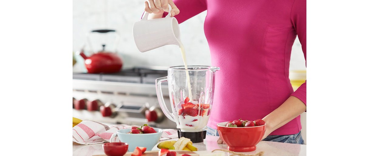 Kvinne tilbereder en proteinshake med Formula 1 og jordbÃ¦r