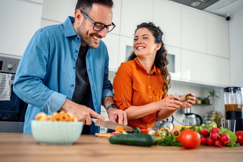 Couple amoureux préparant une salade dans une cuisine.