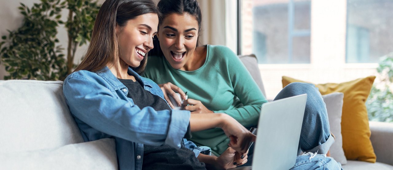 Shot of two happy beautiful women doing a video call sitting on the couch at home.