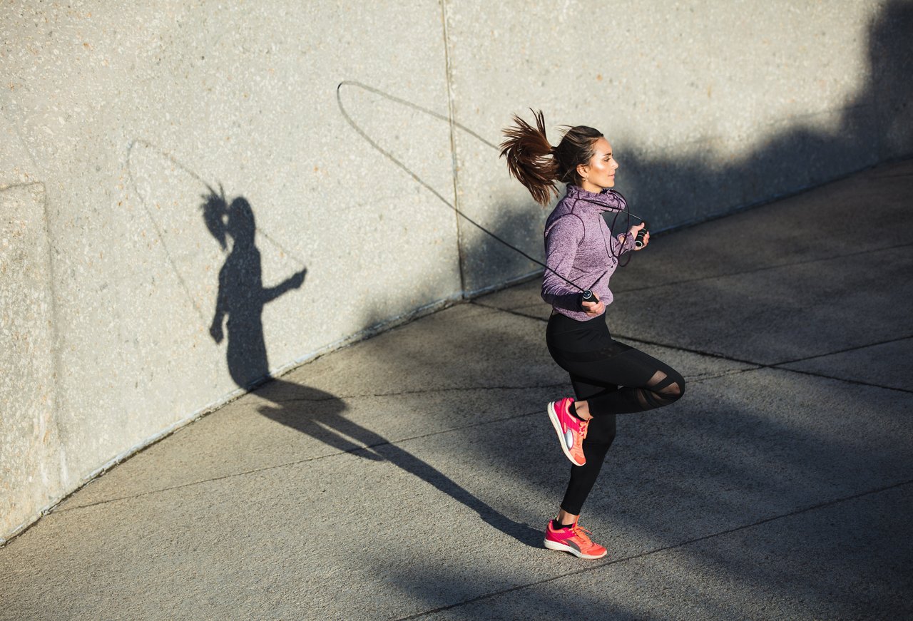 Fitness woman skipping with a jump rope outdoors. Female doing fitness training in morning.