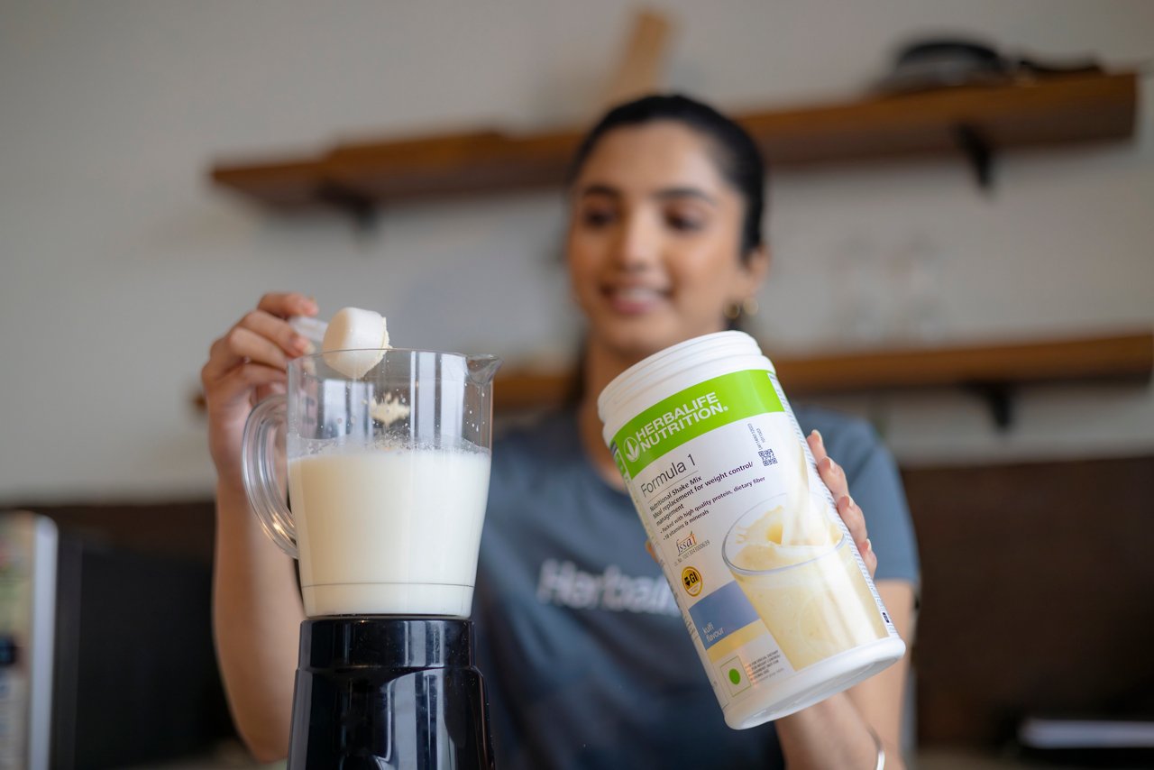 Woman preparing Formula 1 shake in her kitchen