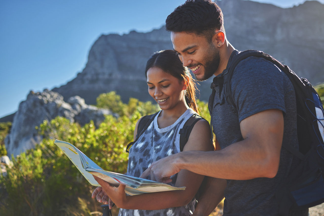 Shot of a young couple using a guide book to complete a hike in a mountain range