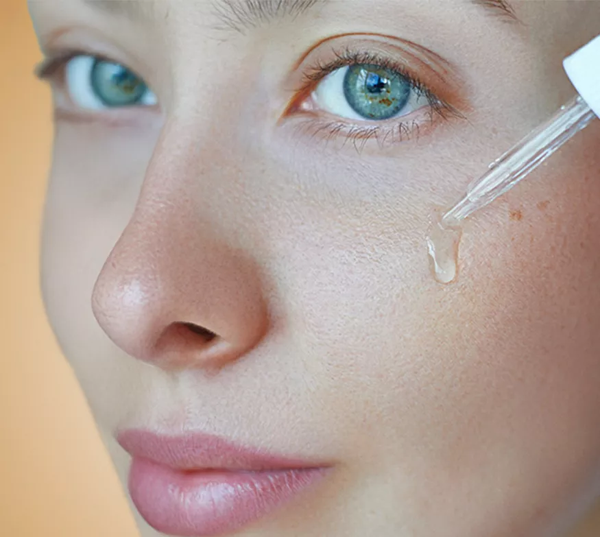 Μια γυναίκα εφαρμόζει τον ορό HL/Skin Niacinamide στο πρόσωπό της.