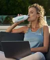 Woman drinking from white bottle outdoors