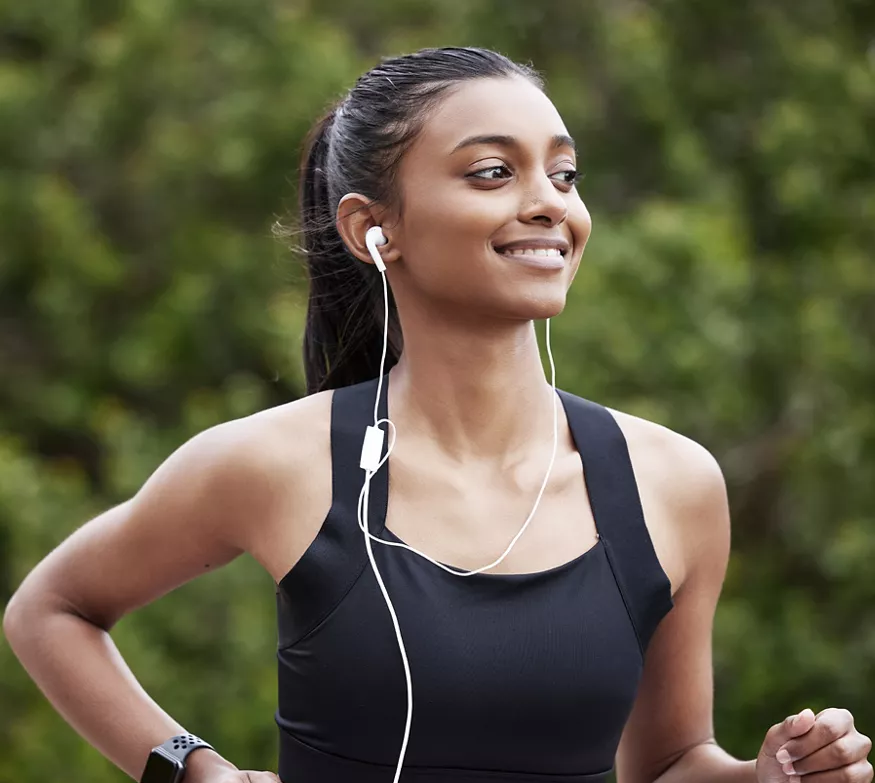 Smiling woman with headphones in on run in the park