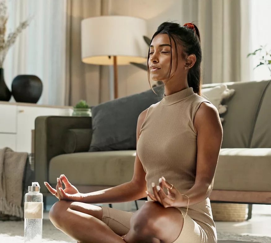 Woman meditating on yoga mat at home