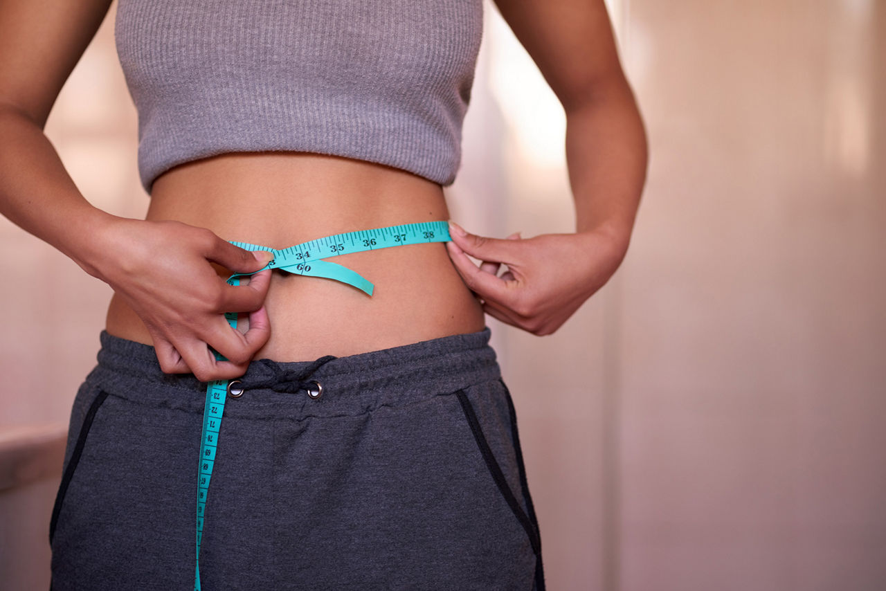 Woman measuring her waist, Person using a digital scale monitor to measure body composition