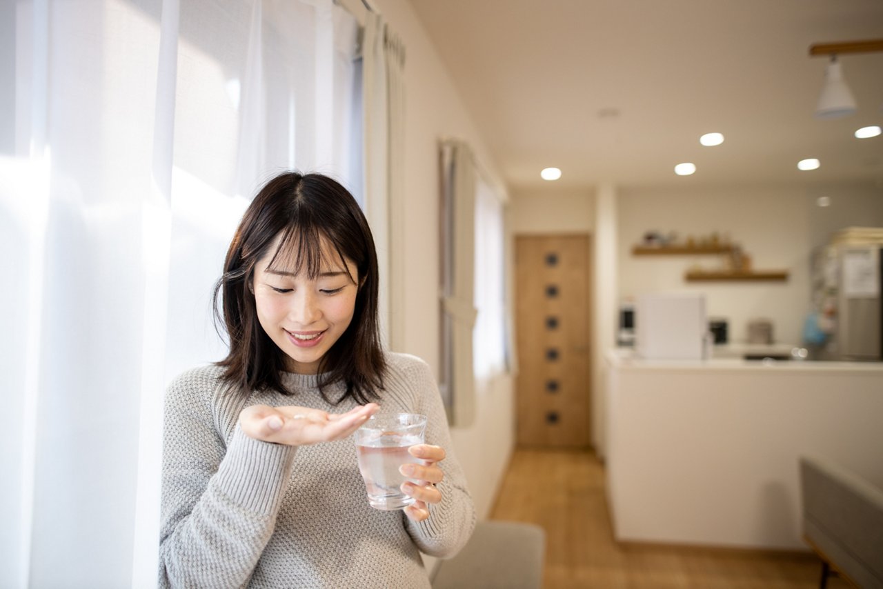 Pregnant woman taking medicine in living room